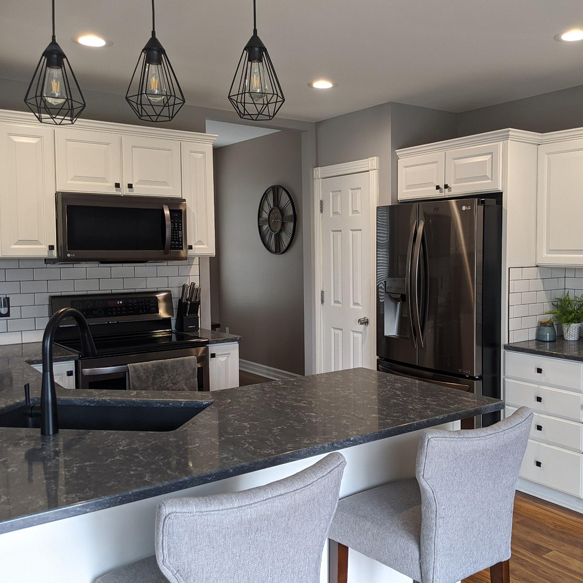 Refinished kitchen with white cabinets and black and grey black splash and counter top 